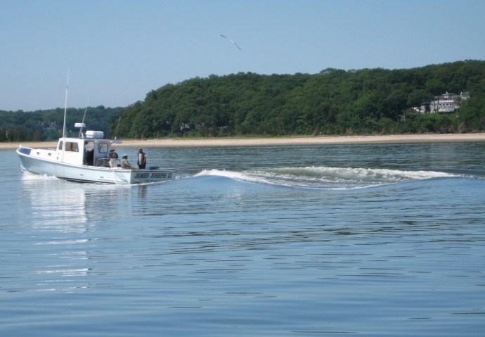 A fishing boat hurries to harbor, leaving behind the only ripples on placid Huntington Bay.