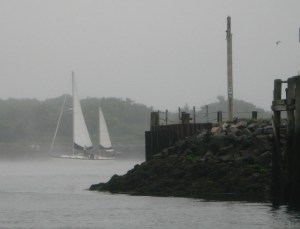 An early morning fog erased the hull of a ketch battling the current.